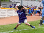 Child in a purple baseball uniform preparing to throw a ball on a baseball field.